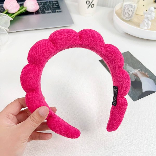 Hot pink plush spa headband held in a hand