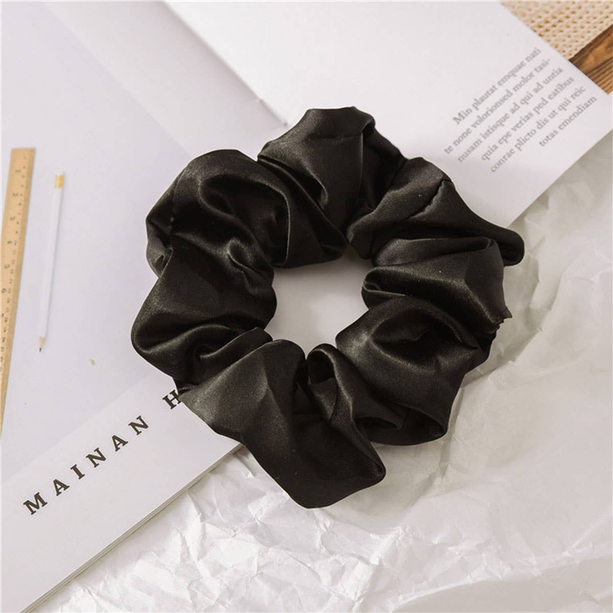 Black satin scrunchie on a white surface