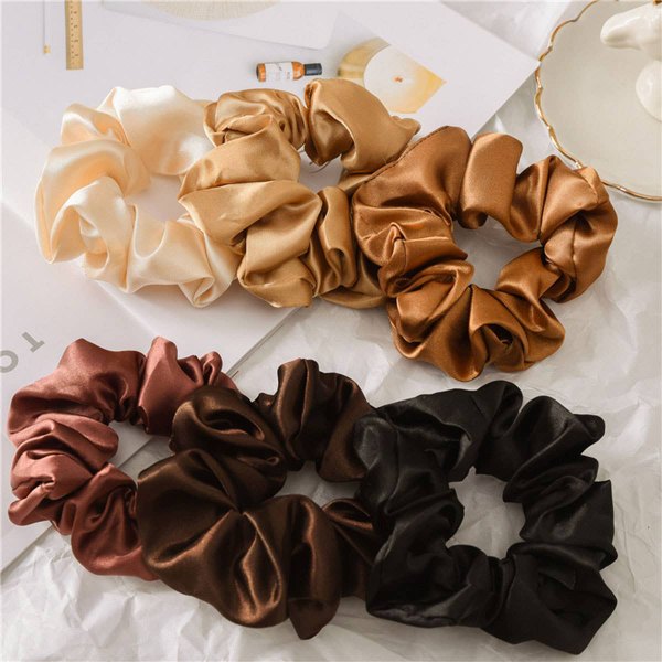 Flat lay of satin scrunchies in cream, tan and black
